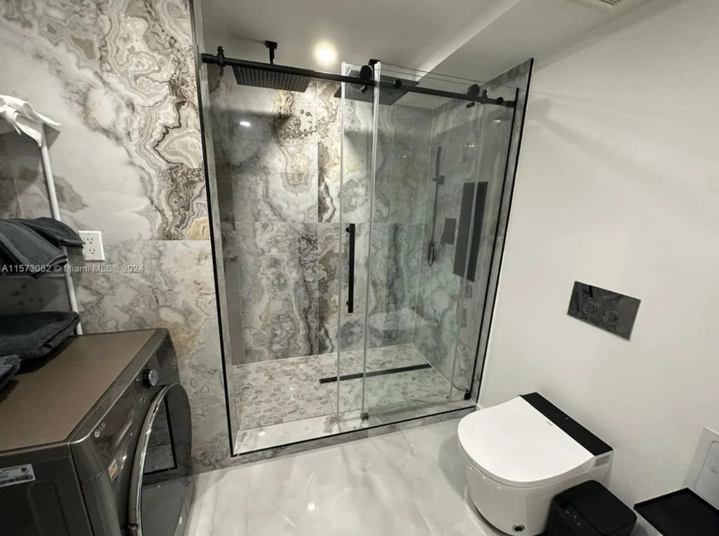Book-matched marble rain shower with glass enclosure